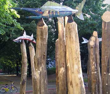 Bild Bunte Holzfische sind an den Spitzen dicker Holzpfälen aufgespießt