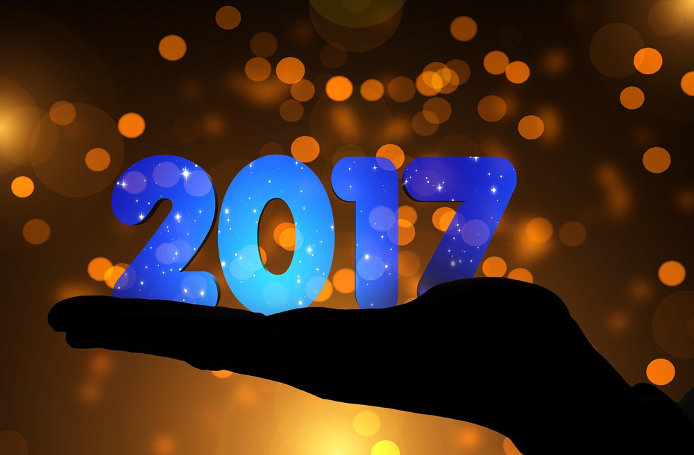 Fotomontage: Silouette einer ausgesteckten Hand, auf der nach oben ausgerichteten Innenseite die Zahlen 2017 in blau stehen. Hintergrund bräunlich-gelb, mit hellen Lichtpunkten.