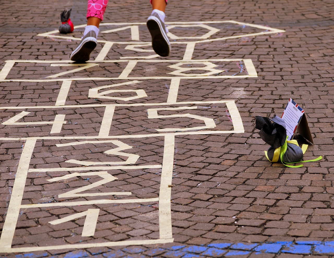 Foto: Kinderfüßen springen über Speil auf Straße