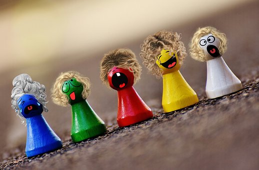 Foto: 5 bunter Holzfiguren als Form Kegel mit Kopf, mit Gesiuht und Haaren. Motiv diagonal v.l.u.n.r.o.