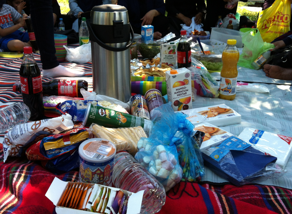 Foto: Eine Picknickdecke auf der Tee. Cola,Saft und viele Süßigkeiten liegen