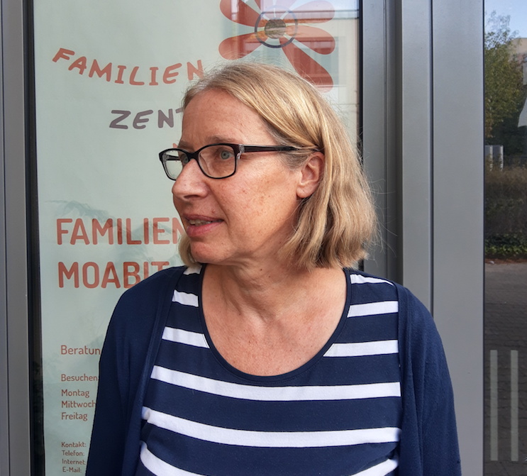 Foto: Portrait von Frau mit Brille, blonden Haaren und blau-weiß gestreiften Hemd, die leicht nach links schaut