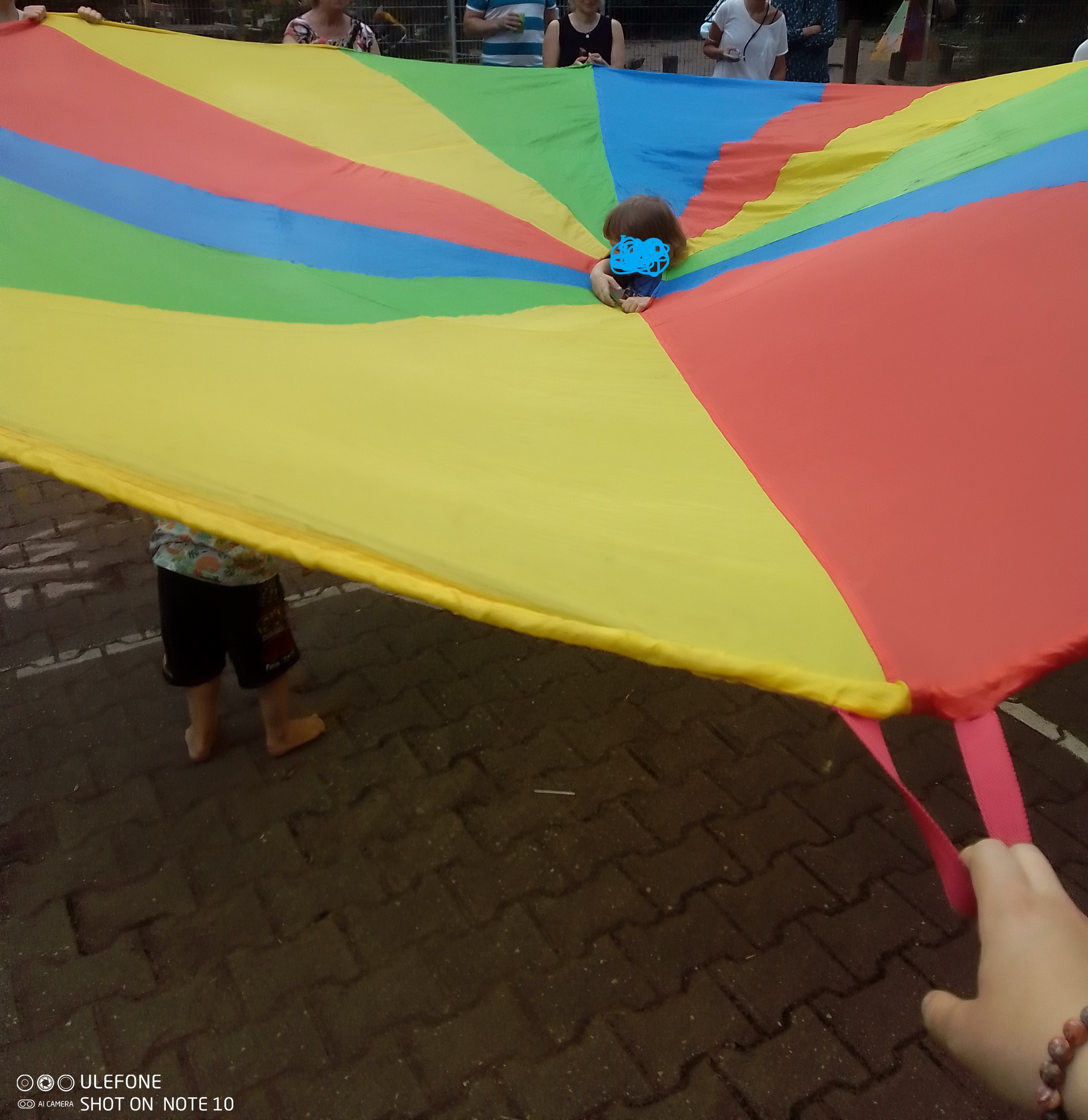 Foto: Ein buntes Schwungtuch, aus dessen Mitte ein Kinderkopf herausschaut